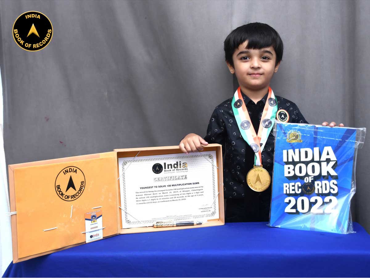 Armaan Ubhrani wearing his India Book of Records medal, beside his framed certificate and the India Book of Records 2022 volume