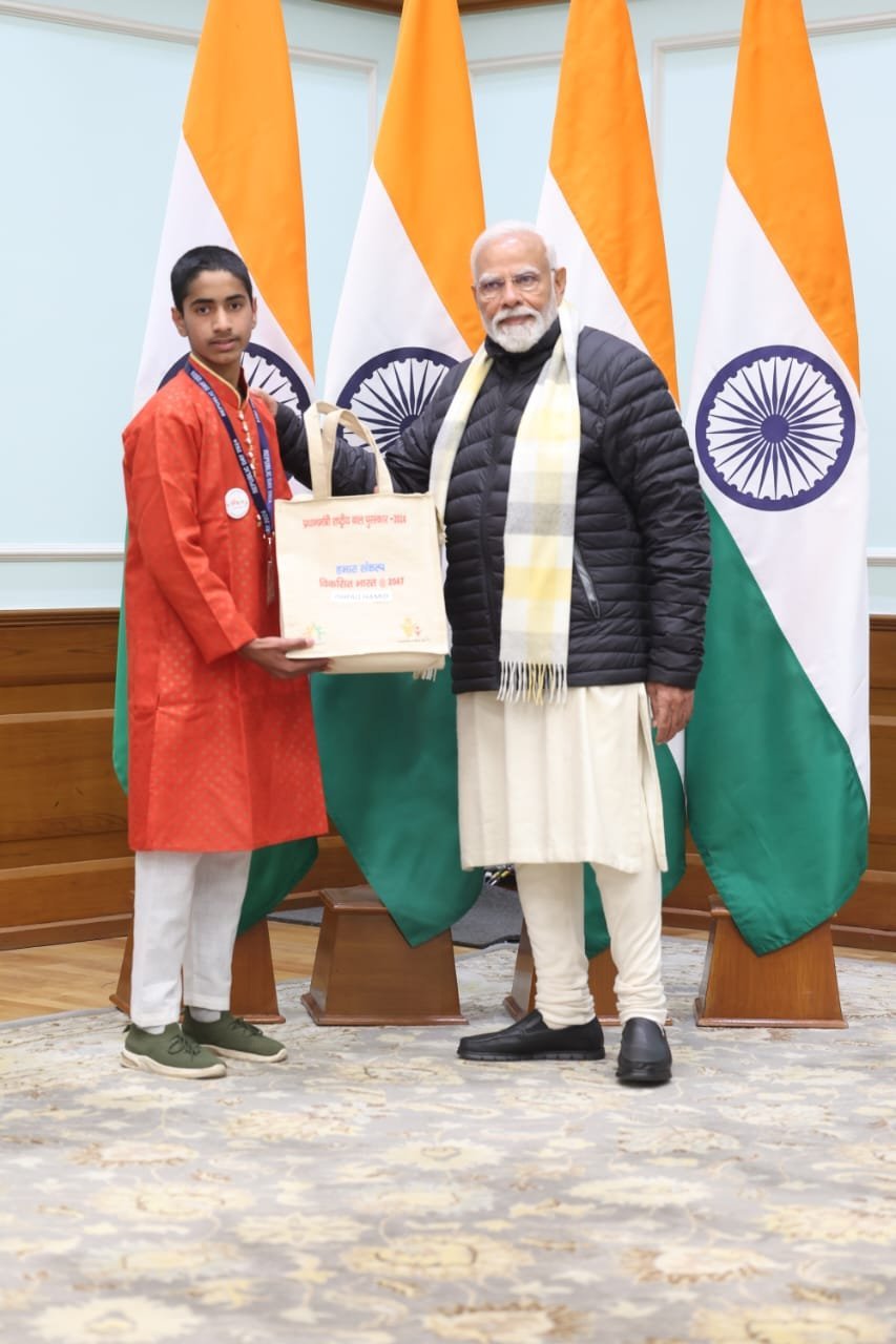 Ishfaq Hamid standing with Prime Minister Narendra Modi, holding his Bal Puraskar 2024 award kit