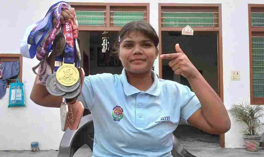 Jyoti holding up her bundle of para-athletics medals at home